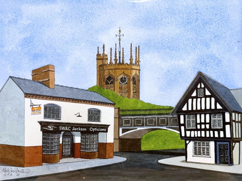 Jacksons Opticians storefront with historic tower in background, in a picturesque town setting.